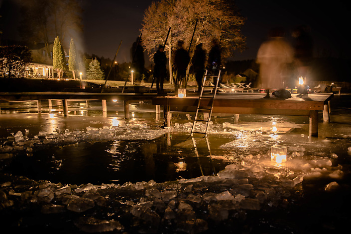 przerębel w lodzie na jeziorze nocą oświetlona świecami przy hotelu Galery69