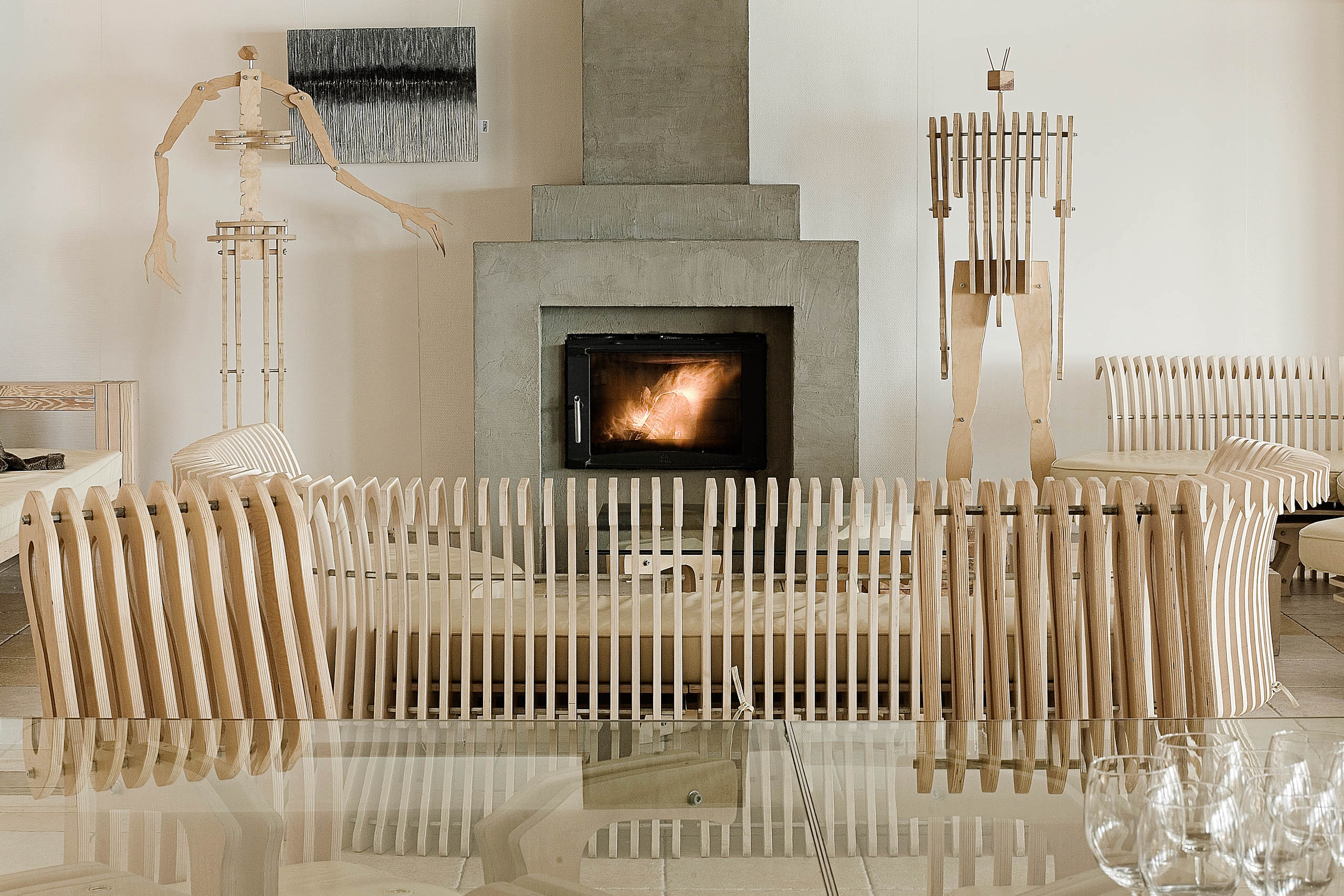 widok restauracji w hotelu Galery69, płonący kominek, szklany stół i kieliszki, wyeksponowane rzeźby - manekiny ze sklejki drewnianej wykonane w Manufaktura69